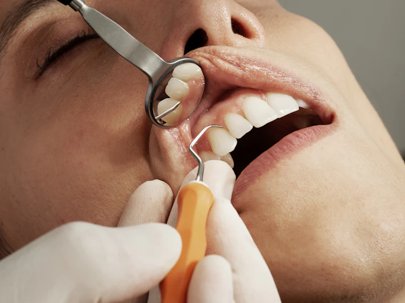 A dentist checking a patient's teeth and gums with a small mirror
